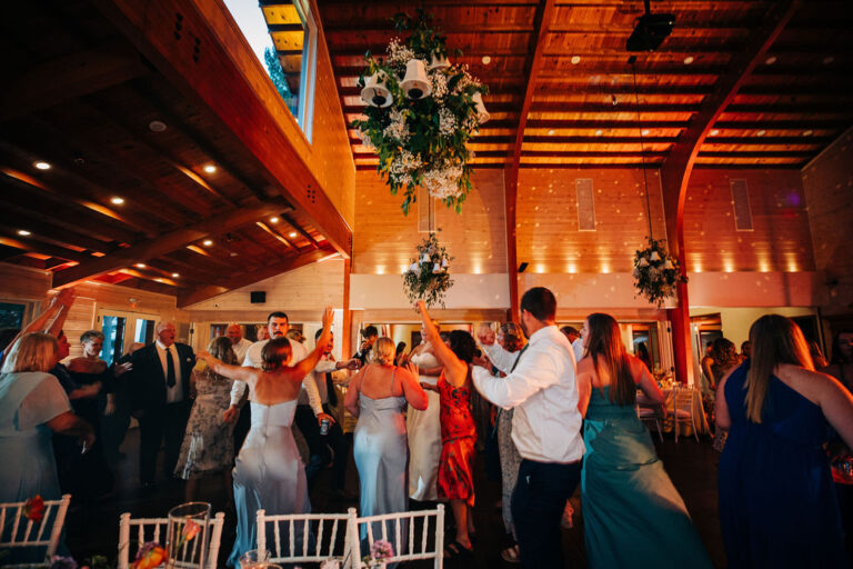late night wedding reception dancing in the main dining room of the White Oak Lodge at Chippewa Retreat Resort in Manitowish Waters Wisconsin. Large mirror ball hangs in the air above a crowd of dancers with dim lighting