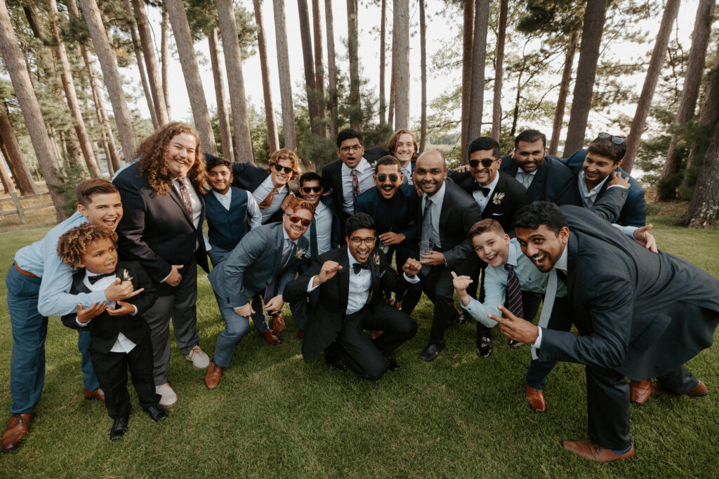 group of guys of many ages and ethnicities posing for a wide angle shot around the groom